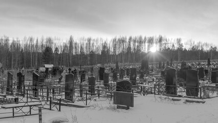Black and white panoramic view of graveyard at sunset. Orthodox traditional cemetery in snowy winter.