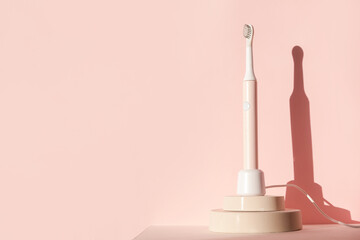 New modern ultrasonic toothbrush. Dental care supplies on cylinder podium on pink pastel background. Oral hygiene, dental and gum health, healthy teeth. Dental products 