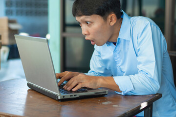Young Asian man looks at laptop screen with excited expression, Business ideas and learning.