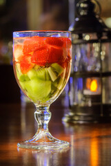 Cocktail drink with strawberries and kiwi fruit on the bar counter with blurred background.