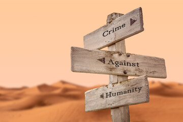 crime against humanity text quote on wooden signpost outdoors in dry desert sand dune scenery.