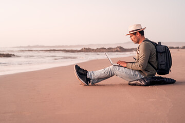 man sitting on the beach outdoors with a laptop alone doing telecommuting or remote work.