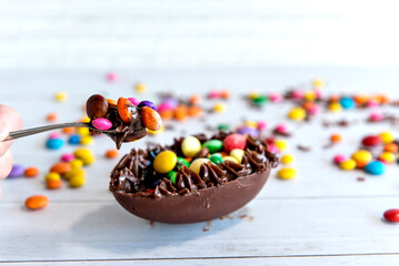 Easter concept, chocolate filled easter egg, selective focus on the spoon with filling