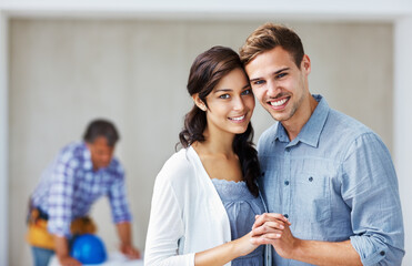 Happy couple smiling with architect in background. Portrait of young loving couple smiling holding hands with architect in background.