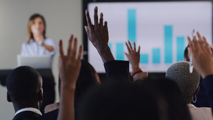 Opening the floor for a QA session. Rearview shot of a group of businesspeople raising their hands during a conference in an office.