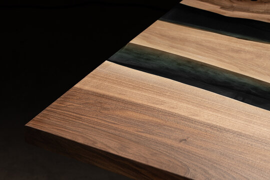 Expensive vintage furniture. The table is covered with epoxy resin and varnished. Luxury quality wood processing. Wooden table on a dark background. Black river made of epoxy resin.