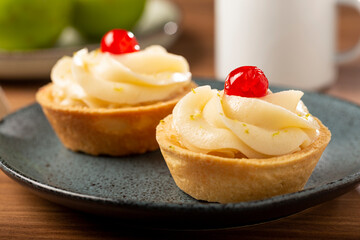 Lemon tartlets decorated with cherry.