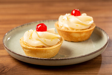 Lemon tartlets decorated with cherry.