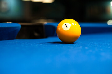 yellow billiard ball floor number one is lying on the table with a blurred background