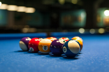 multicolored billiard balls lie in a triangle on a table with a blurred background