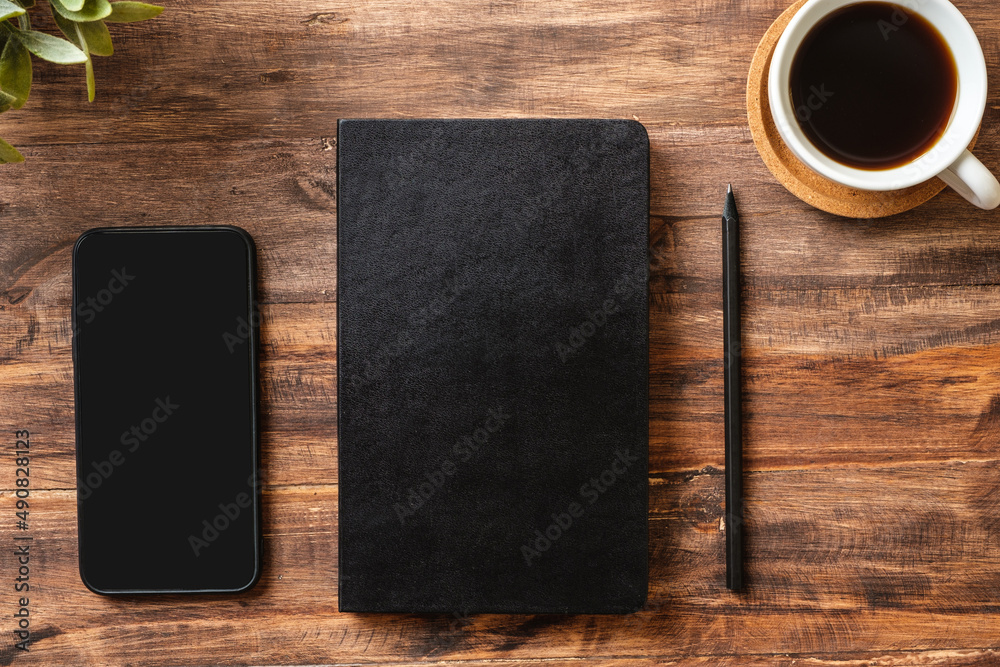 Poster top view working desk with close notebook and mobile phone,coffee cup on wooden table background