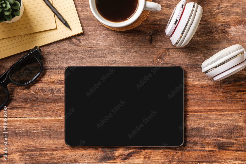 Poster top view working desk with tablet ,keyboard headphone on wooden table background