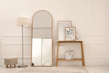 Obraz na płótnie Canvas Beautiful mirror, console table and lamp near white wall indoors. Interior design