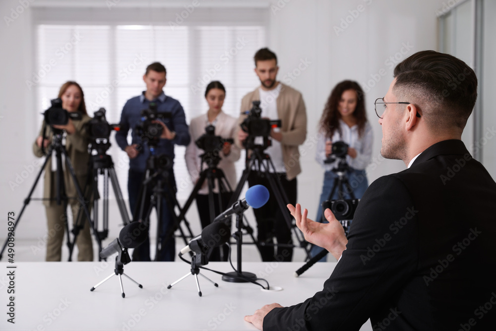 Wall mural Businessman giving interview to journalists at official event