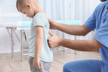 Orthopedist examining child's back in clinic, closeup. Scoliosis treatment