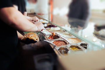 Cook putting tomatoes sauce in a Flat Bread Sandwich