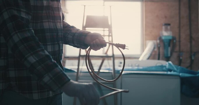 Man in garage coils an extension cord