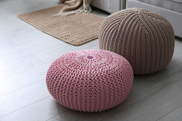 Stylish knitted poufs on floor in living room. Interior element
