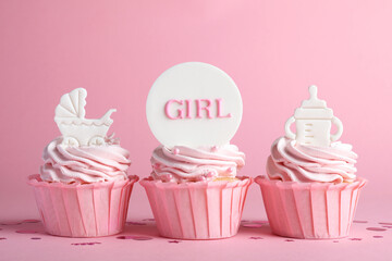 Beautifully decorated baby shower cupcakes for girl with cream and toppers on pink background
