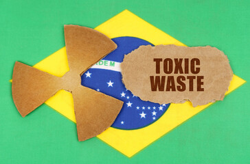 On the flag of Brazil, the symbol of radioactivity and torn cardboard with the inscription - Toxic...