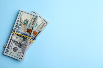Bundles of dollar banknotes on light blue background, top view. Space for text