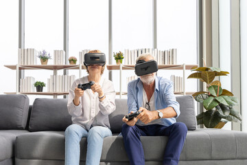Obraz premium senior couple playing game and having fun together with virtual reality headset on the sofa