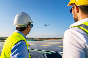 Professional engineer using drone and digital tablet maintaining solar cell panels together on...