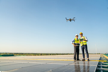 Professional engineer using drone and digital tablet maintaining solar cell panels together on building rooftop. Technician working on ecological solar farm. Renewable clean energy technology concept © CandyRetriever 