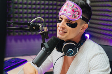 A funny radio presenter in a sleep mask, bathrobe and cosmetic patches