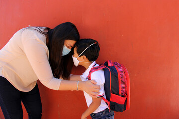 Latino mom and son prepare to go back to school with a backpack and face mask as protection from...