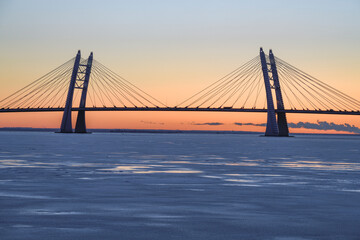 Fototapeta na wymiar The silhouette of the cable-stayed bridge over the Ship Fairway on the Western High-Speed ​ ​ Diameter against the background of the December sunset. St. Petersburg, Russia