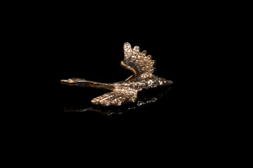 Silver brooch in the form of a flying swan on a black background