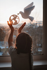 child stretches his hands sunlight outside window flying dove world with branch forces globe. concept peace world, no war, ecology - obrazy, fototapety, plakaty