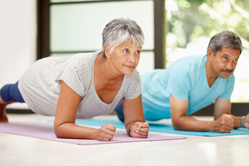 We keep each other focused on fitness. Shot of a mature couple exercising together at home.