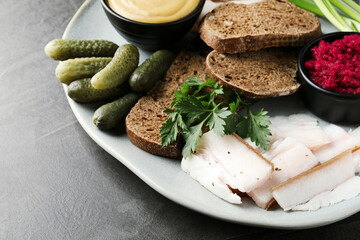 Tasty salt pork with rye bread and sauces served on grey table