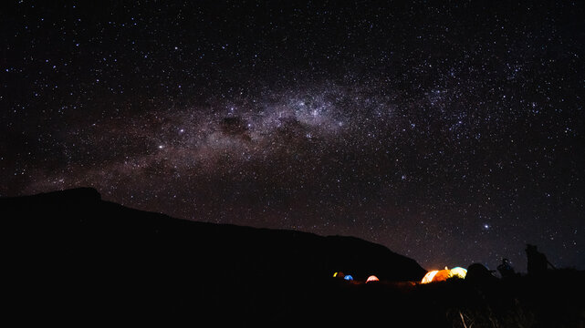 Amazing night scenery with beautiful milky way on the sky with camping tent in the foreground at Senaru Crater Rim, Mount Rinjani Indonesia. (noise grain soft focus visible due to long exposure)