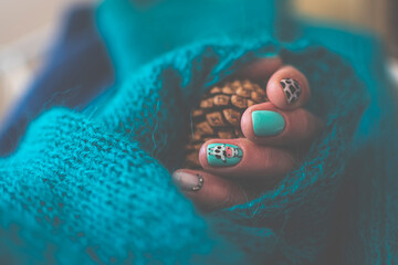 Creative bright manicure design for summer. Cow fur pattern, funny cartoon painting, blue knitted sweater. Selective focus on the details, blurred background.