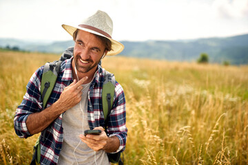  .Hipster guy on the nature listens to music.happy man with backpack and smartphone