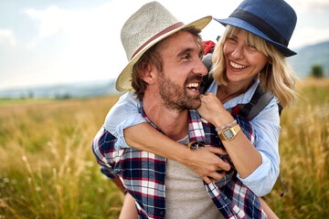 Meeting in the nature. man carrying his girlfriend on piggyback.