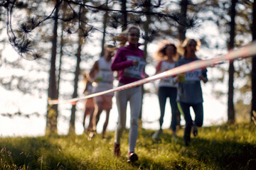 Blurred photo of group of athletes running through forest. Marathon in the forest. Sport, running,...