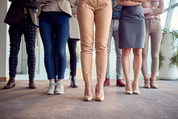 Close-up shot of young business team's legs standing in the company building hallway and posing for a photo. Business, people, company