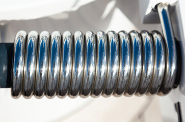 Stainless steel spring on the door hinge for quick closing, close-up.