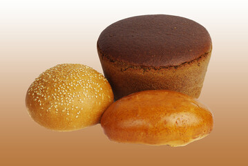 A loaf of black bread, a bun and a patty on a brown background.