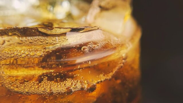 Soda is pouring into a glass with ice cubes isolated on a black background. Overflowing wet glass with pop soda. 4k macro video 60 fps.