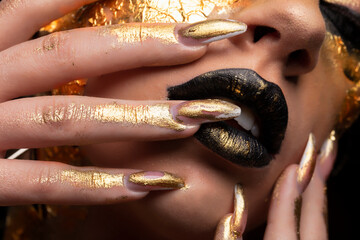 Beauty fashion model girl with golden make-up and body on black background. Golden body art. The...