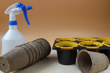 plastic and peat containers for planting plants and a sprayer on a wooden table