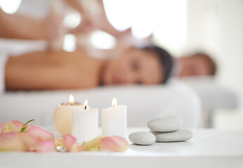 Blissful relaxation. A married couple receiving massages at a spa with candles in the foreground.