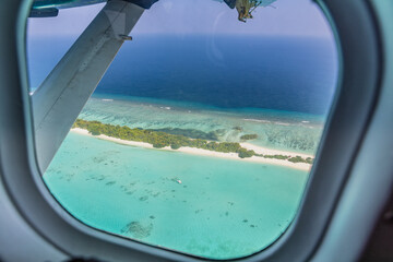 Airplane window with beautiful Maldives island view. Luxury summer holiday travel tourism...