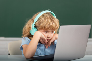 Serious child boy in headphones study online, child in earphones take Internet web lesson.