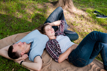 A young couple, a guy and a girl, relax in the park in the summer